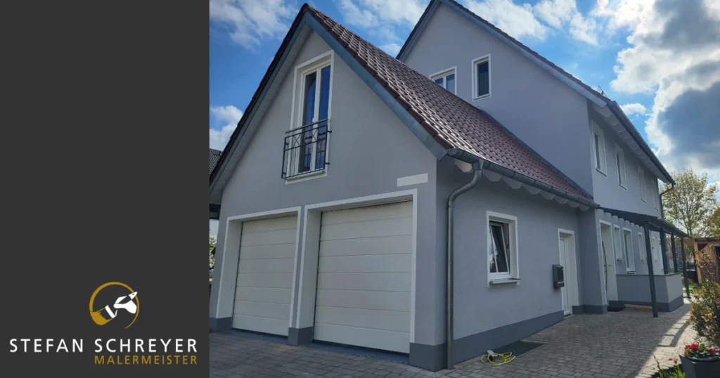 Hausfassade in Hellgrau mit weißen Fensterumrahmungen und Dachuntersicht nach dem Fassadenanstrich